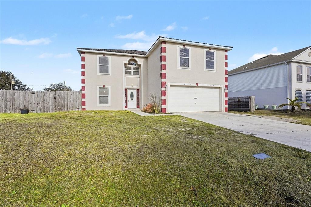 A two-story house with a beige stucco exterior and red-trimmed corners features a two-car garage — 194 ABALONE ROAD NW, PALM BAY, FL