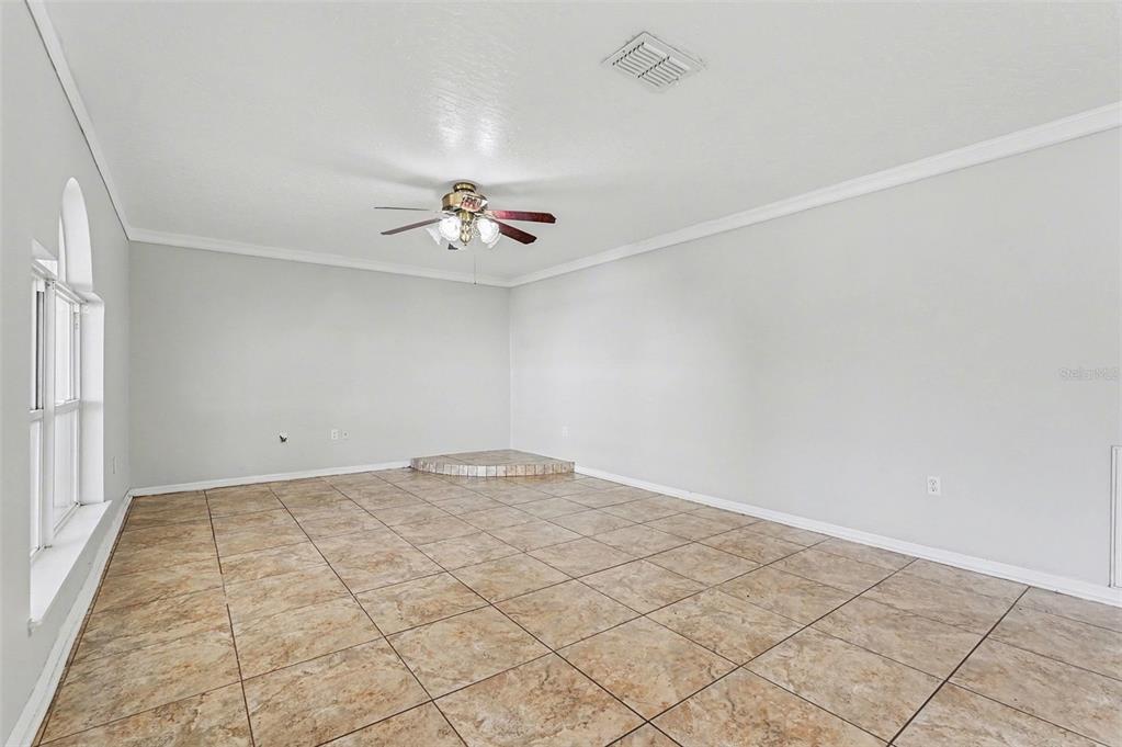 An empty room with light gray walls, large tan floor tiles, and a ceiling fan — 194 ABALONE ROAD NW, PALM BAY, FL