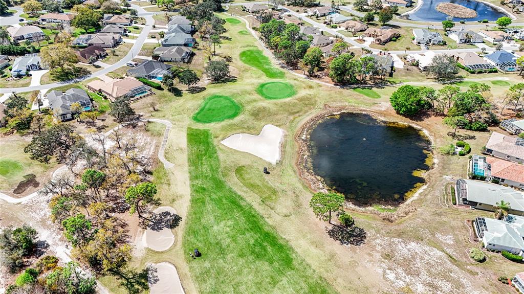 An aerial view shows a golf course fairway with a sand trap and a pond — 9196 PLAYERS DRIVE, WEEKI WACHEE, FL