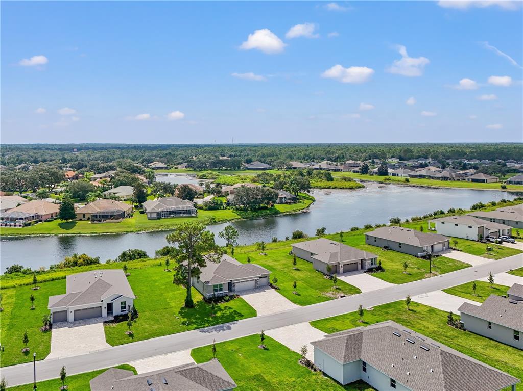 An aerial view shows suburban houses with green lawns situated along a large lake — 9196 PLAYERS DRIVE, WEEKI WACHEE, FL