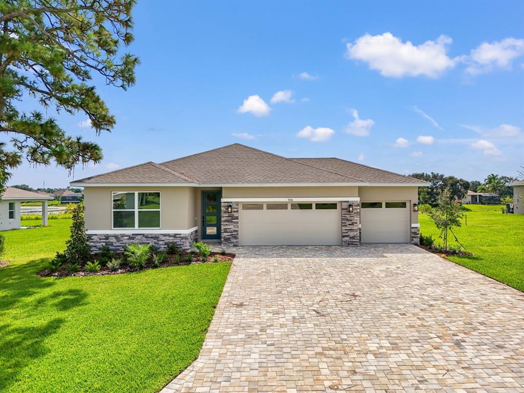 A single-story house with a stone-accented facade, a three-car garage, and a paved driveway — 9196 PLAYERS DRIVE, WEEKI WACHEE, FL