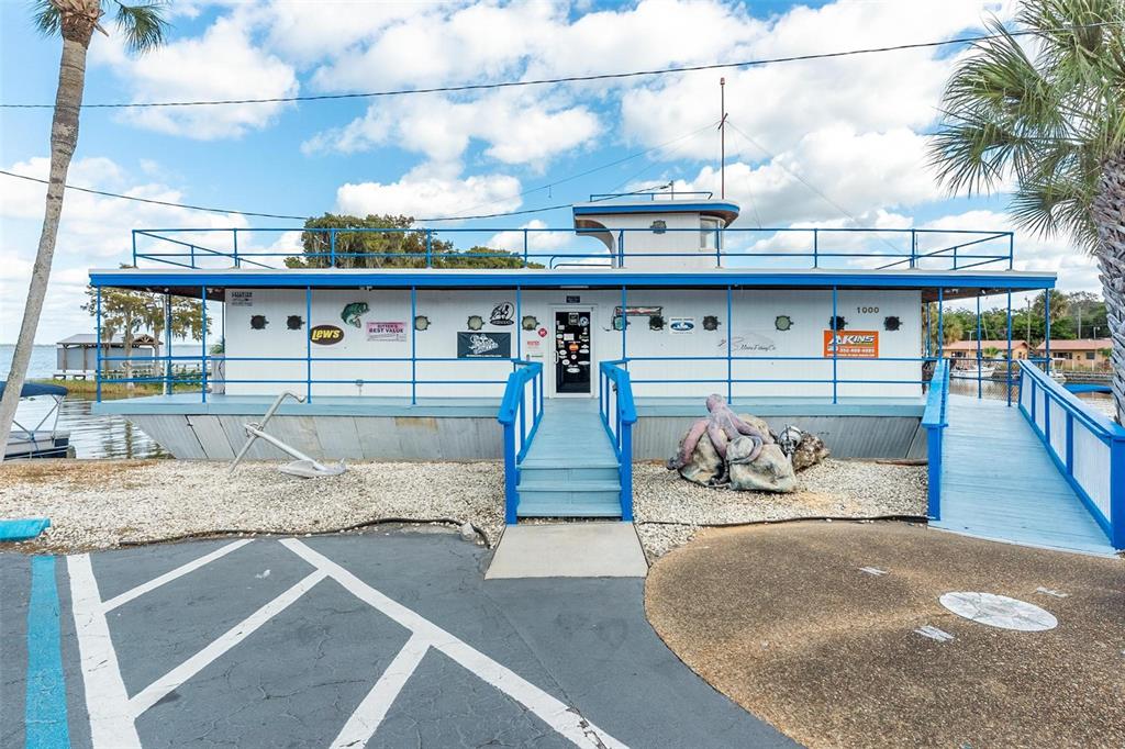 A boat-shaped building with a blue railing, stairs, and an anchor sits near water — 1006 W BURLEIGH BOULEVARD, TAVARES, FL