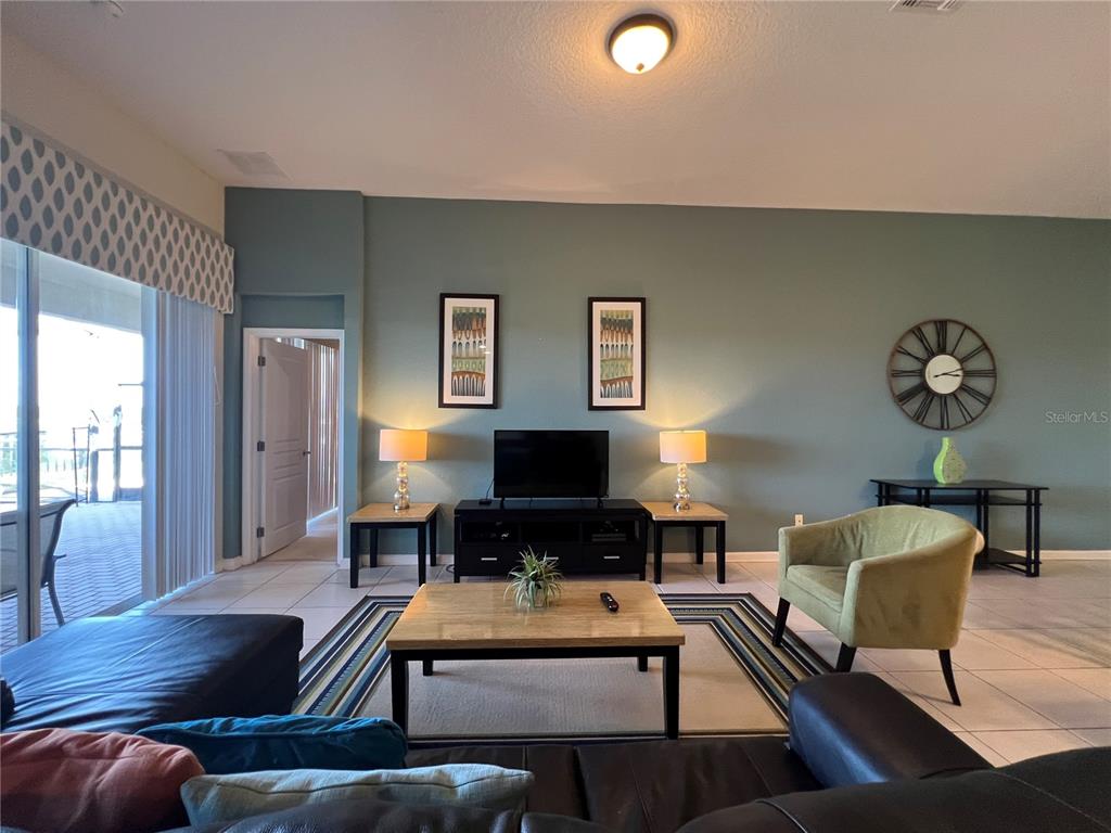 A living room features a dark leather sectional, a central coffee table, and a television console — 2568 ARCHFELD BOULEVARD, KISSIMMEE, FL