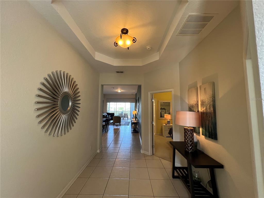 A tiled entryway leads into a living area with a tray ceiling and light fixture — 2568 ARCHFELD BOULEVARD, KISSIMMEE, FL
