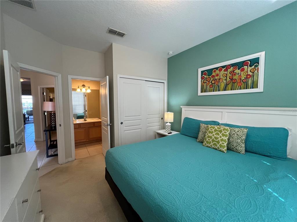A bedroom features a teal accent wall, a king bed, and an attached bathroom — 2568 ARCHFELD BOULEVARD, KISSIMMEE, FL