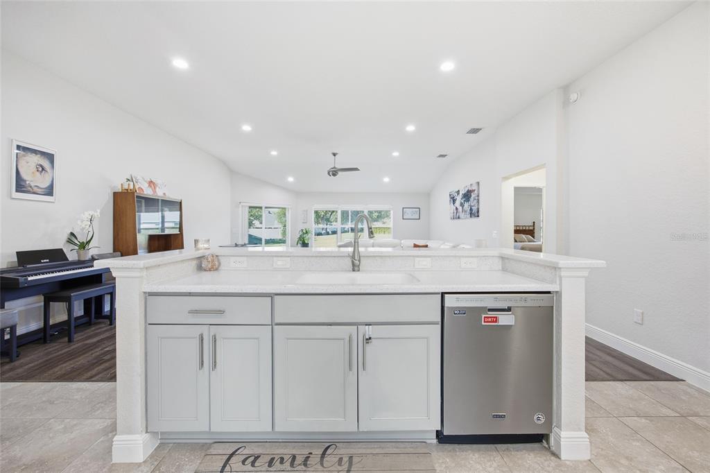 A kitchen island with a sink and dishwasher faces an open-concept living area — 4846 AUDREY MARIE COURT, OXFORD, FL