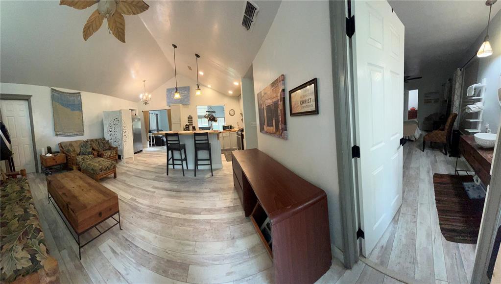 An open-concept living area features a vaulted ceiling, wood-look flooring, and a kitchen island — 2535 NW 49TH PLACE, GAINESVILLE, FL