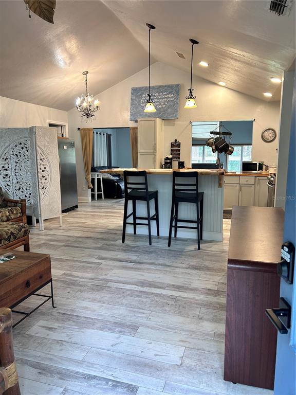 A kitchen with a breakfast bar, pendant lighting, and wood-look flooring opens to a living area — 2535 NW 49TH PLACE, GAINESVILLE, FL