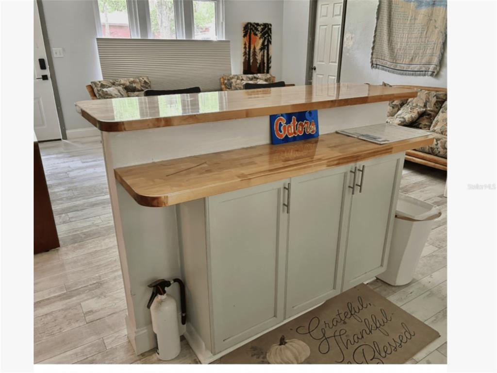 A kitchen island with a light wood countertop and light gray cabinets sits on tile flooring — 2535 NW 49TH PLACE, GAINESVILLE, FL