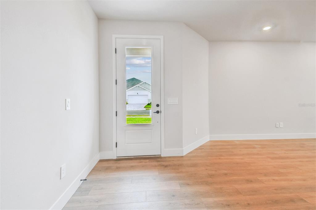 An interior room features light wood-look flooring, white walls, and a door with glass panels — 2836 MARRAKESH LANE, SARASOTA, FL