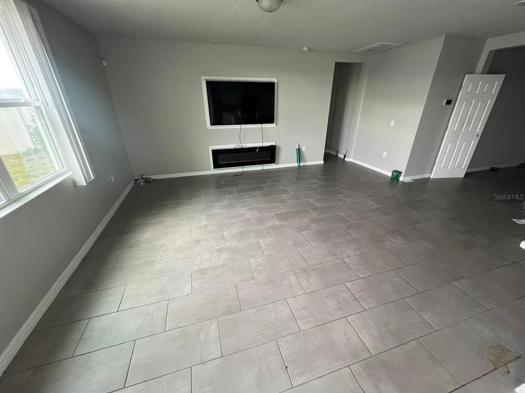 A living room features gray tile flooring, a wall-mounted television, and a built-in fireplace — 528 MCKENNA DRIVE, WINTER HAVEN, FL