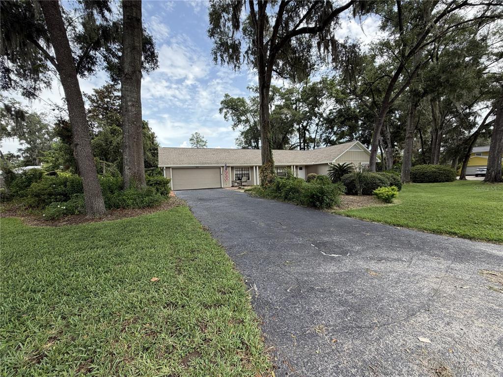 A single-story house with a tan exterior, a two-car garage, and a long asphalt driveway — 3925 SE 17TH STREET, OCALA, FL