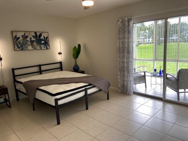 A bedroom features a metal bed frame, tile flooring, and a sliding glass door to a patio — 1011 Berkshire A # 1011, Deerfield Beach FL 33442, DEERFIELD BEACH, FL