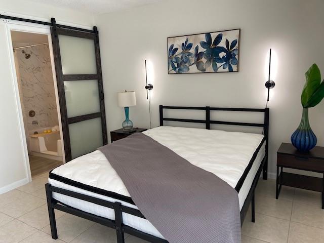A bedroom features a metal bed frame, a sliding barn door, and wall-mounted light fixtures — 1011 Berkshire A # 1011, Deerfield Beach FL 33442, DEERFIELD BEACH, FL