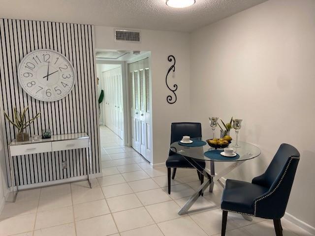A dining area features a glass table, two blue chairs, and a striped accent wall — 1011 Berkshire A # 1011, Deerfield Beach FL 33442, DEERFIELD BEACH, FL