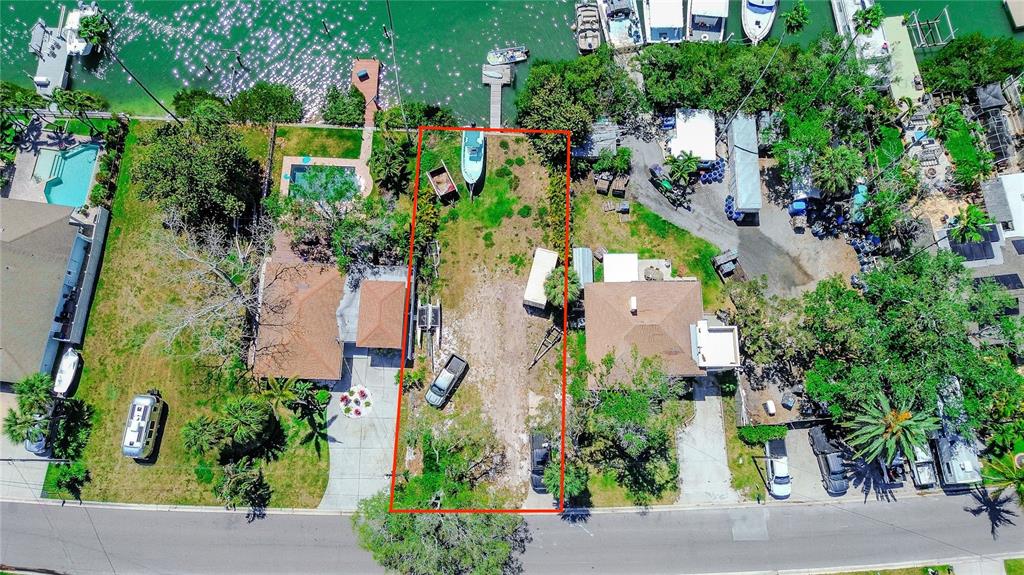 An aerial view shows a vacant rectangular lot situated between two houses near a waterway — 317 12TH AVENUE, INDIAN ROCKS BEACH, FL