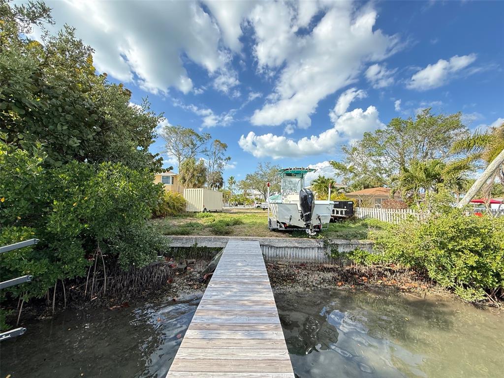 A wooden dock extends toward a boat on a trailer parked on a grassy lot — 317 12TH AVENUE, INDIAN ROCKS BEACH, FL