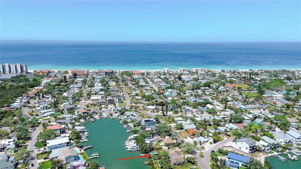 An aerial view shows a coastal neighborhood with a canal and the ocean beyond — 317 12TH AVENUE, INDIAN ROCKS BEACH, FL