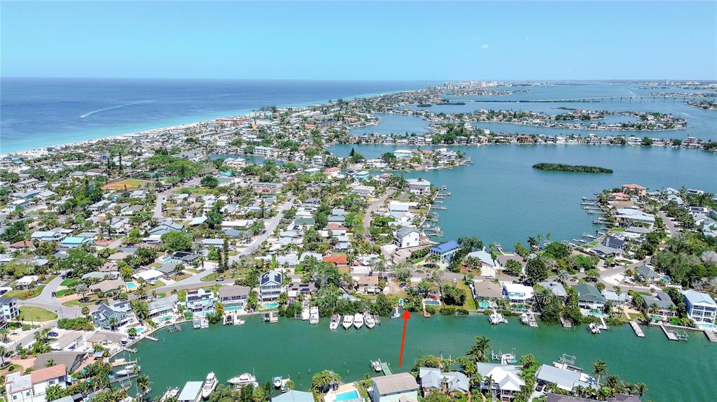 An aerial view shows a waterfront residential neighborhood with a red arrow pointing toward a property — 317 12TH AVENUE, INDIAN ROCKS BEACH, FL