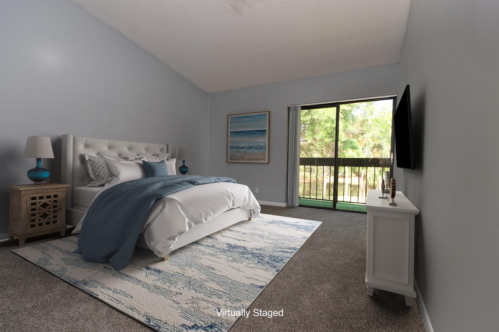 A bedroom with a tufted headboard, blue bedding, a rug, and a sliding glass door — 5087 Oakhill Lane, Delray Beach FL 33484, DELRAY BEACH, FL