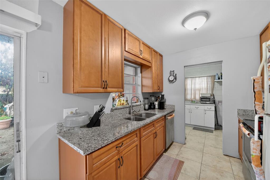 A kitchen features wood cabinets, granite countertops, a double sink, and a tiled floor — 470 WURST ROAD, OCOEE, FL