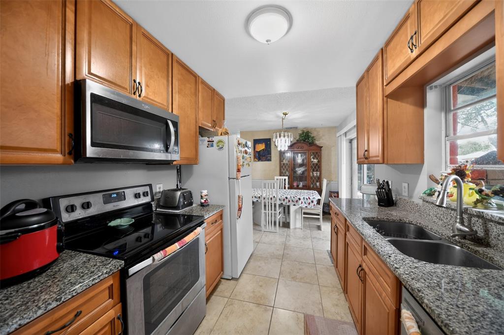 A kitchen with wood cabinets, granite countertops, stainless steel appliances, and an adjacent dining area — 470 WURST ROAD, OCOEE, FL