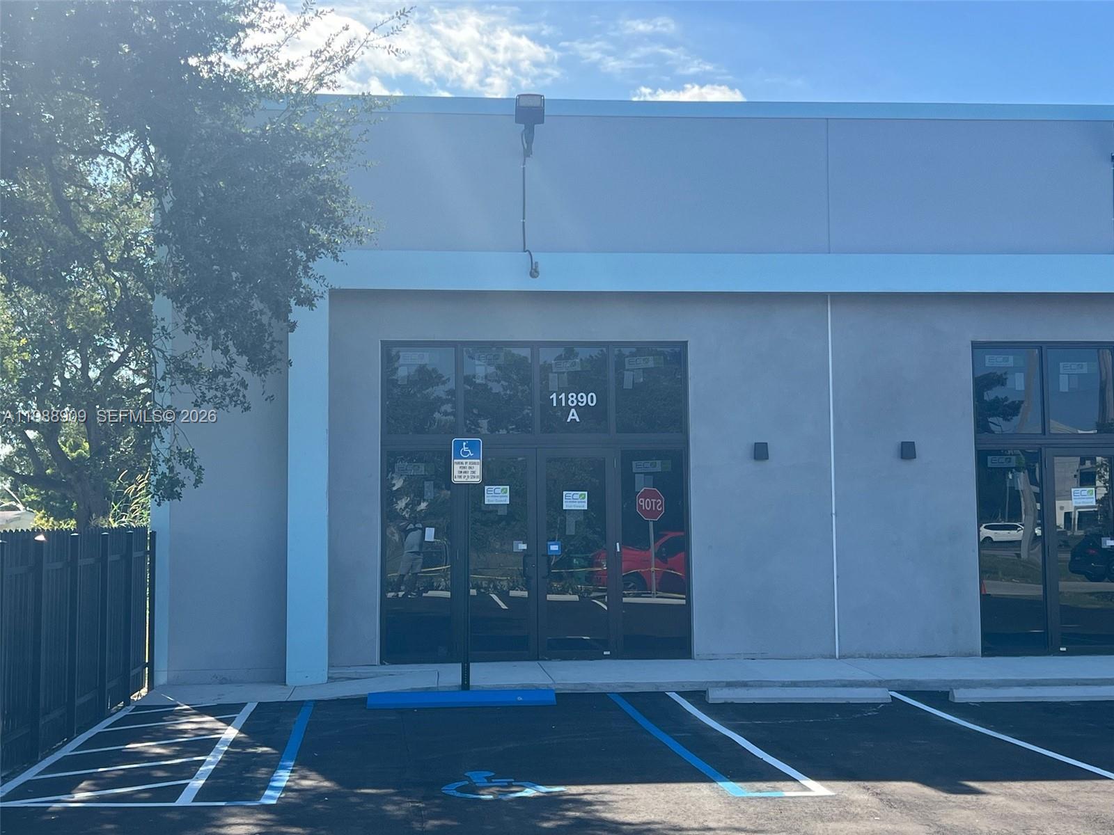 A commercial building exterior features a glass entrance door with a handicap parking space — 11890 SW 220th St, Miami FL 33170, MIAMI, FL