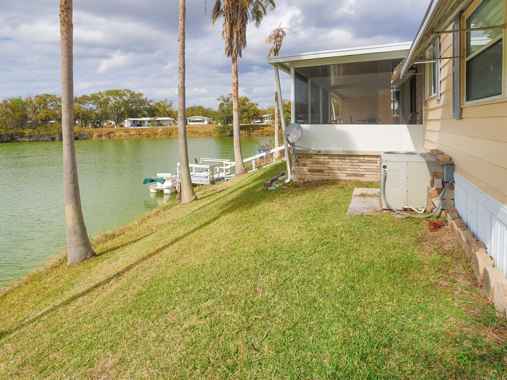 A grassy backyard slopes down to a lake next to a house with a porch — 2055 S FLORAL AVENUE UNIT 238, BARTOW, FL