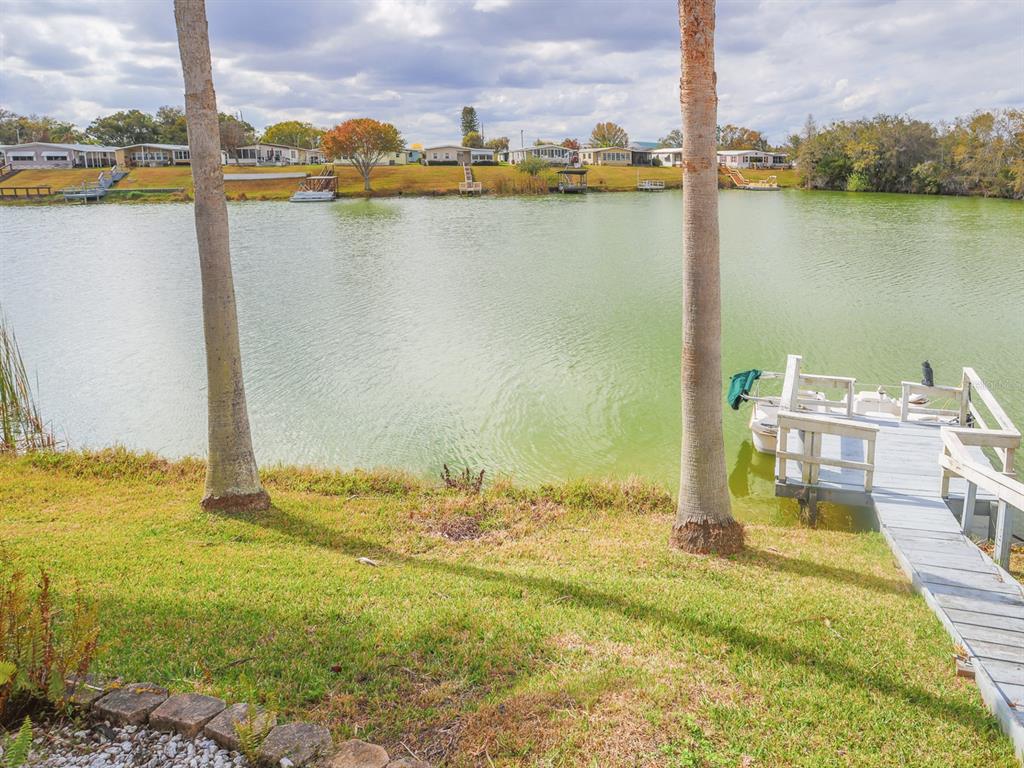 A grassy yard with two palm trees overlooks a lake with a wooden boat dock — 2055 S FLORAL AVENUE UNIT 238, BARTOW, FL