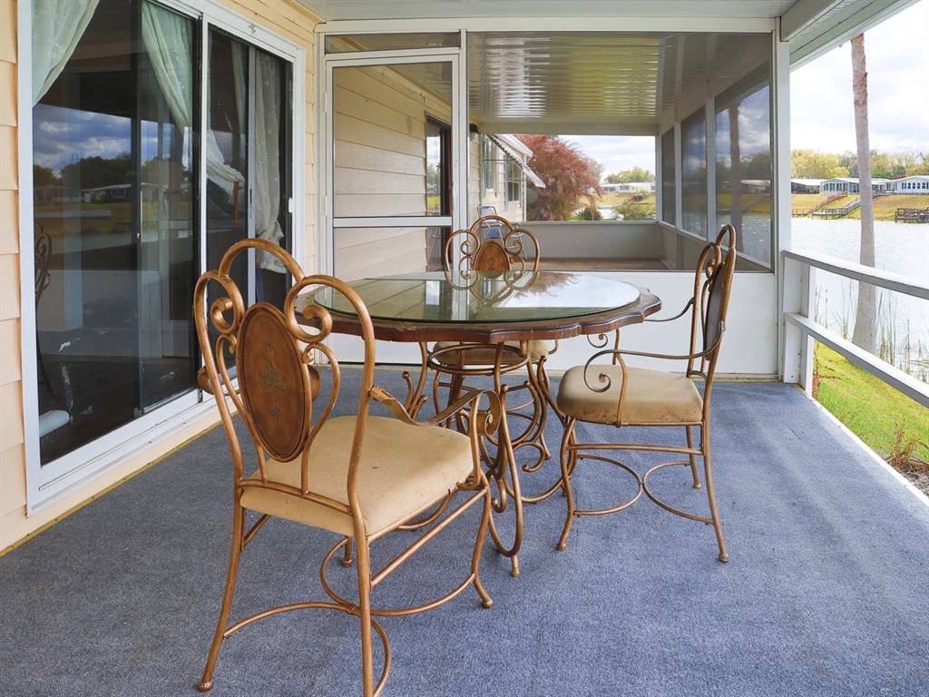A screened-in porch features a glass-topped dining set and views of a nearby lake — 2055 S FLORAL AVENUE UNIT 238, BARTOW, FL