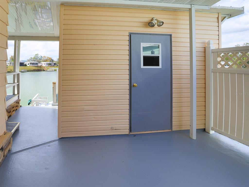 A covered patio features light-colored vinyl siding, a gray door, and a view of water — 2055 S FLORAL AVENUE UNIT 238, BARTOW, FL