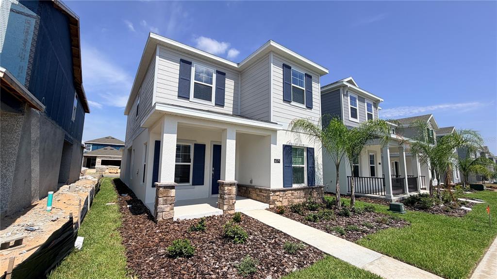 A two-story house with light siding, blue shutters, and a stone-accented front porch — 6079 WELLBEING WAY, CLERMONT, FL