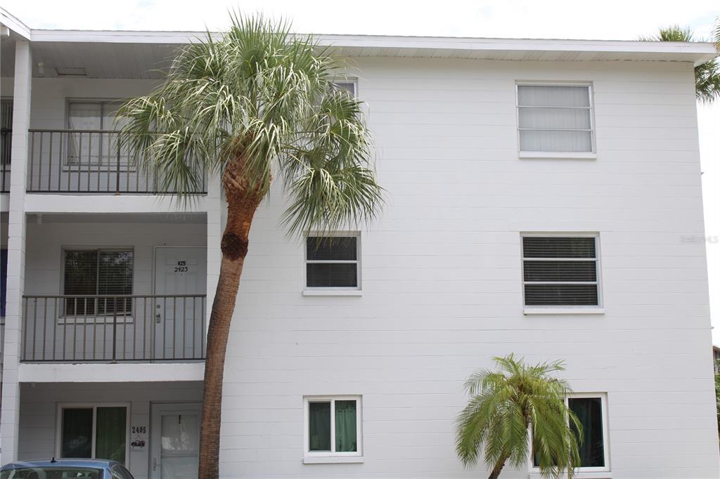 A white three-story apartment building features balconies, palm trees, and several windows — 2423 60TH AVENUE W UNIT K29, BRADENTON, FL
