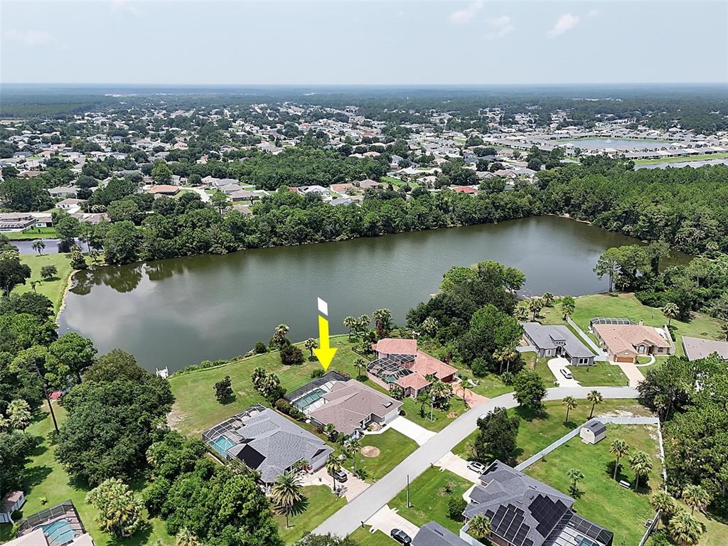 An aerial view shows a residential house with a screened pool near a lake — 41 LUTHER DRIVE, PALM COAST, FL