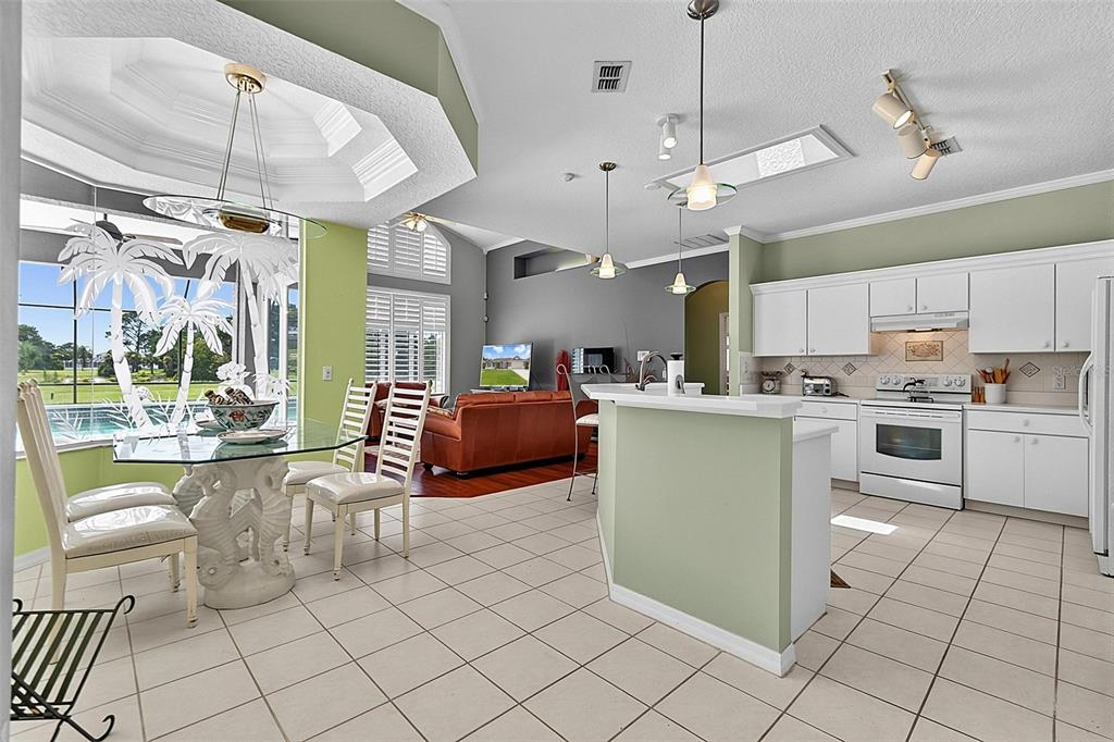 An open-concept kitchen and dining area features white cabinetry, tile flooring, and a glass table — 41 LUTHER DRIVE, PALM COAST, FL