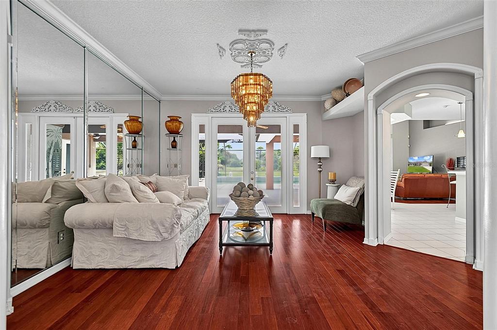 A living room features hardwood floors, a tiered chandelier, mirrored walls, and a glass-topped table — 41 LUTHER DRIVE, PALM COAST, FL