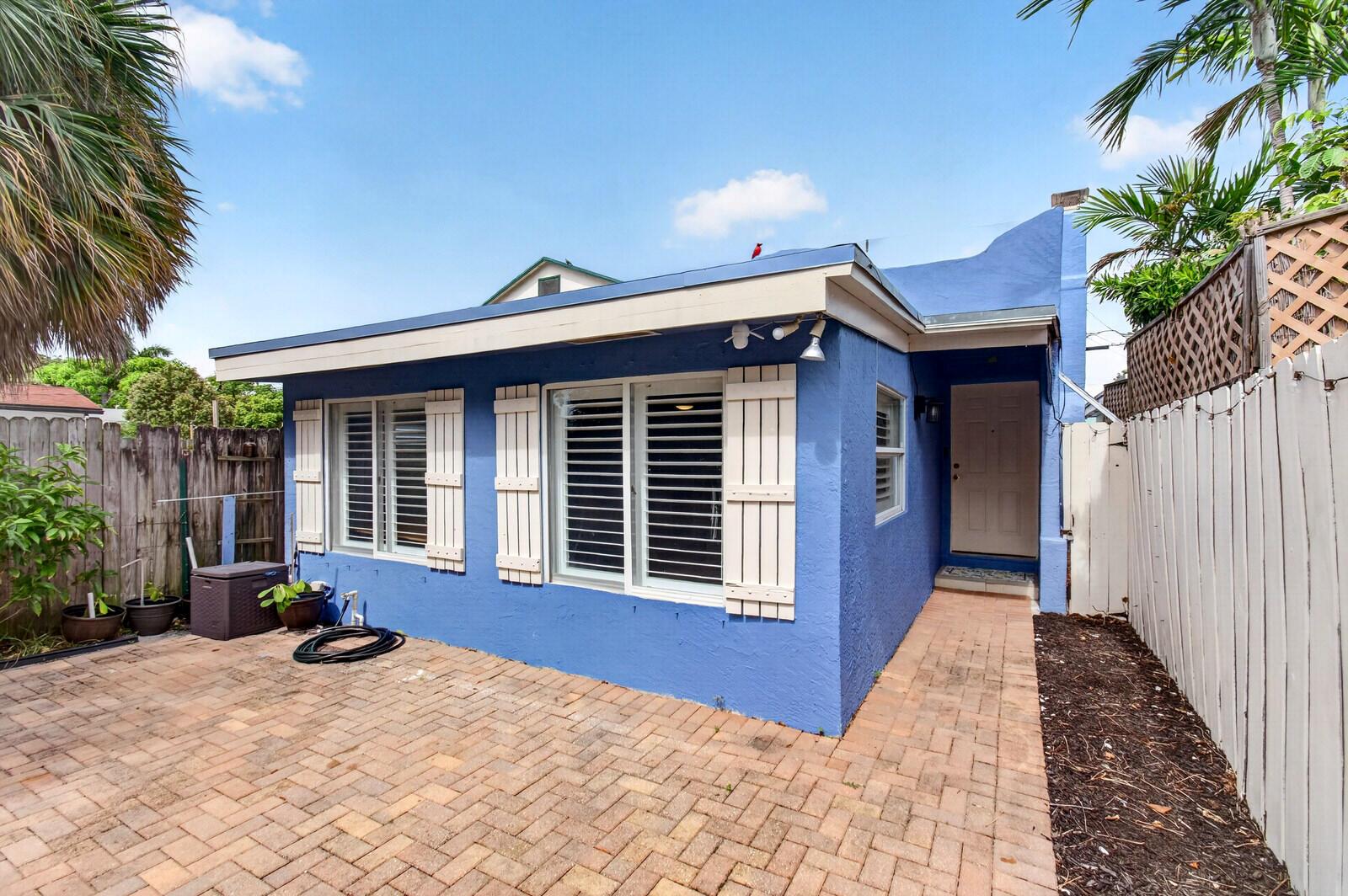 A blue exterior house with white shutters and a brick patio in a fenced yard — 227 N M Street, FL 33460, FL