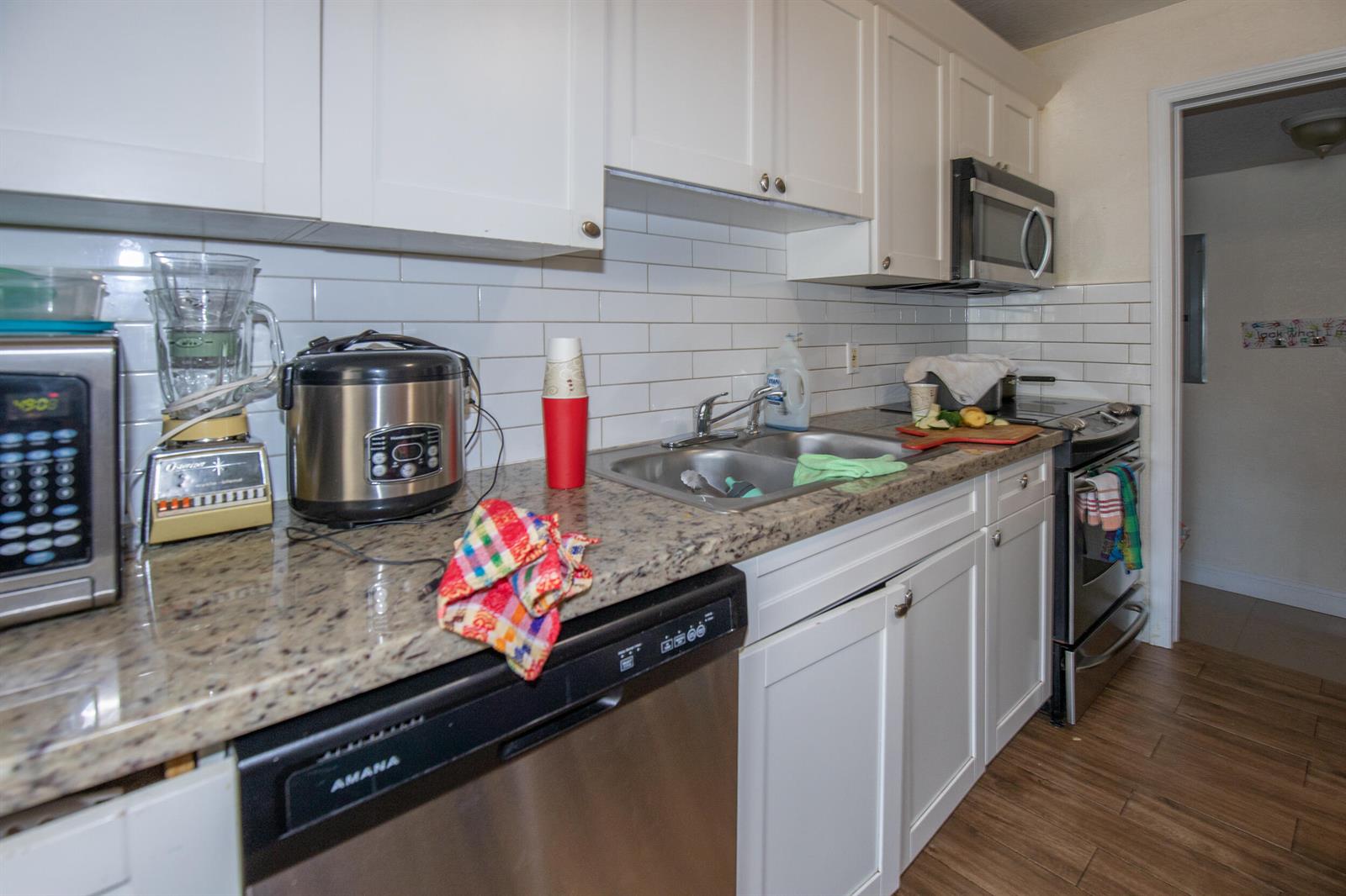 A kitchen features white cabinets, granite countertops, stainless steel appliances, and a white subway tile backsplash — 922 S Dixie Street, FL 33460, FL