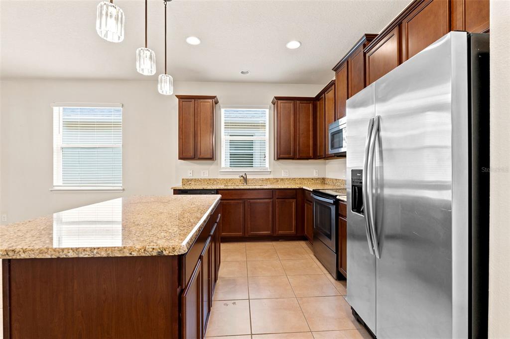 A kitchen features dark wood cabinets, granite countertops, stainless steel appliances, and a central island — 4850 SOUTHLAWN AVENUE, ORLANDO, FL