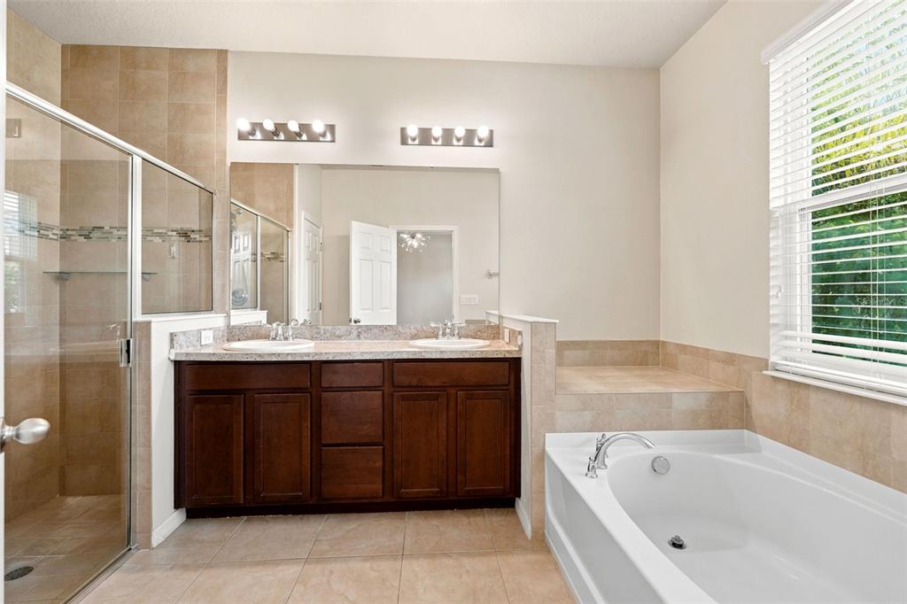 A bathroom features a double vanity, a glass-enclosed shower, and a large soaking tub — 4850 SOUTHLAWN AVENUE, ORLANDO, FL