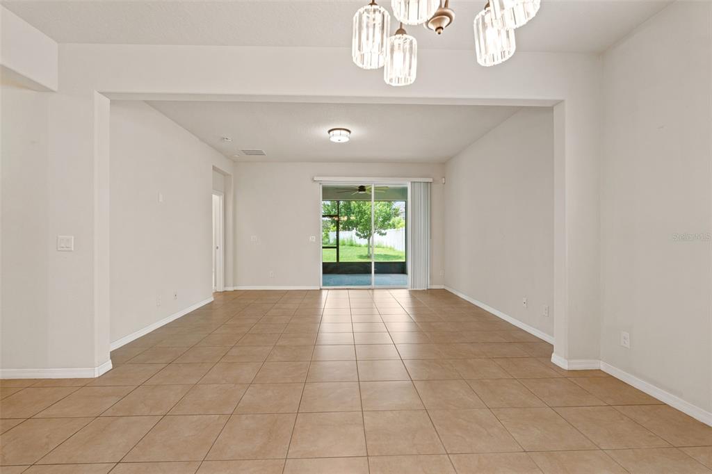 An open-concept living area features beige tile flooring, neutral walls, and sliding glass doors — 4850 SOUTHLAWN AVENUE, ORLANDO, FL