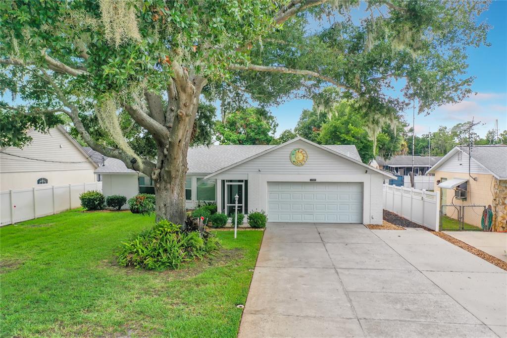 A single-story house with a white garage, a large oak tree, and a white fence — 33909 LINDA LANE, LEESBURG, FL
