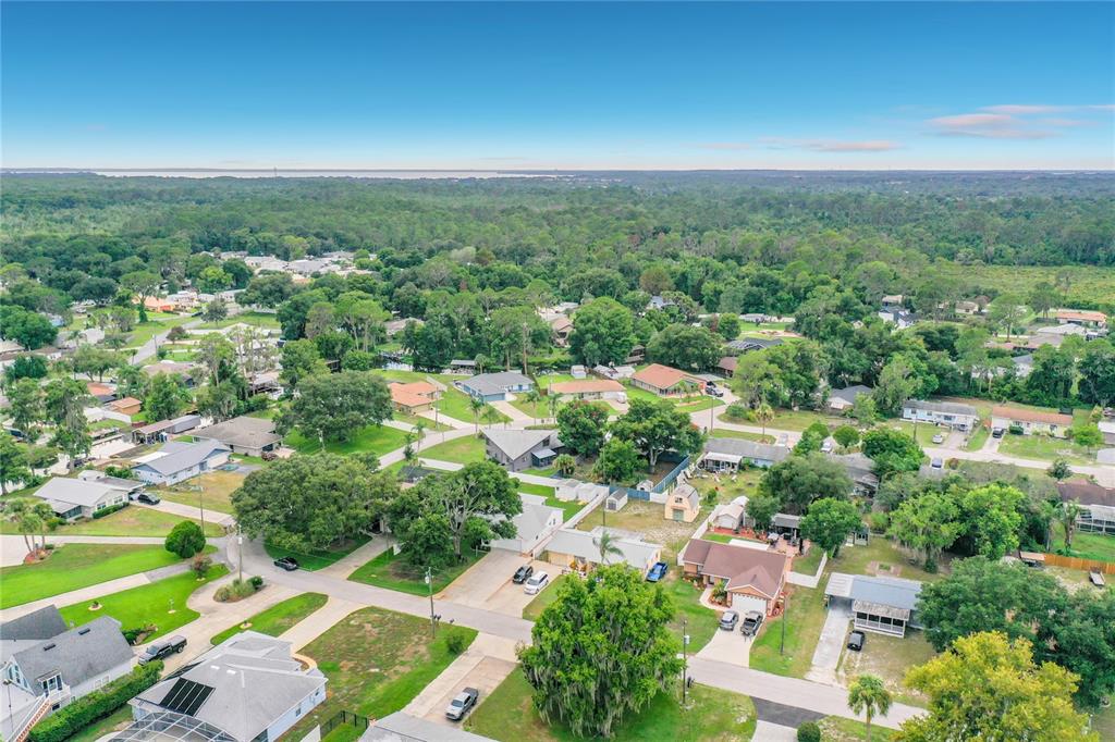 An aerial view shows a suburban neighborhood with houses, green trees, and paved streets — 33909 LINDA LANE, LEESBURG, FL