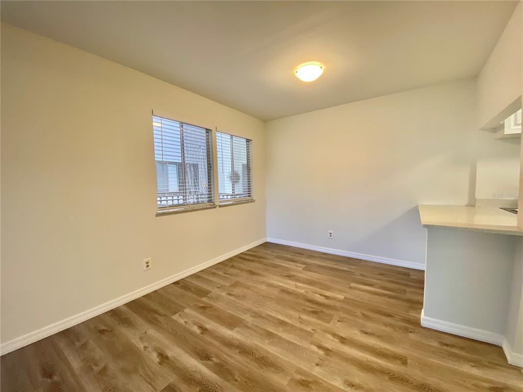 An empty dining area features light-colored walls, wood-look flooring, two windows, and a breakfast bar — 6519 W NEWBERRY ROAD UNIT 1211, GAINESVILLE, FL