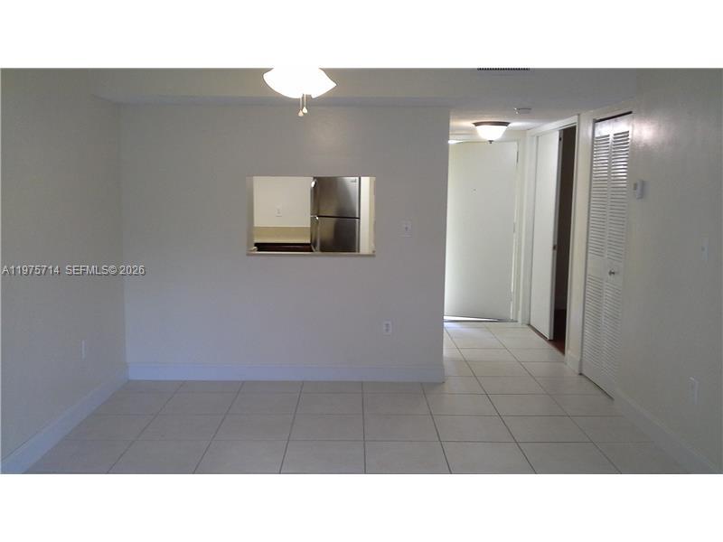 A room with white tile floors, a pass-through window to the kitchen, and louvered doors — 8255 SW 152nd Ave # 309, Miami FL 33193, MIAMI, FL