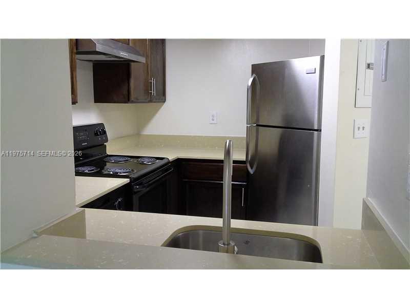 A kitchen features a stainless steel refrigerator, dark wood cabinets, and a stainless steel sink — 8255 SW 152nd Ave # 309, Miami FL 33193, MIAMI, FL