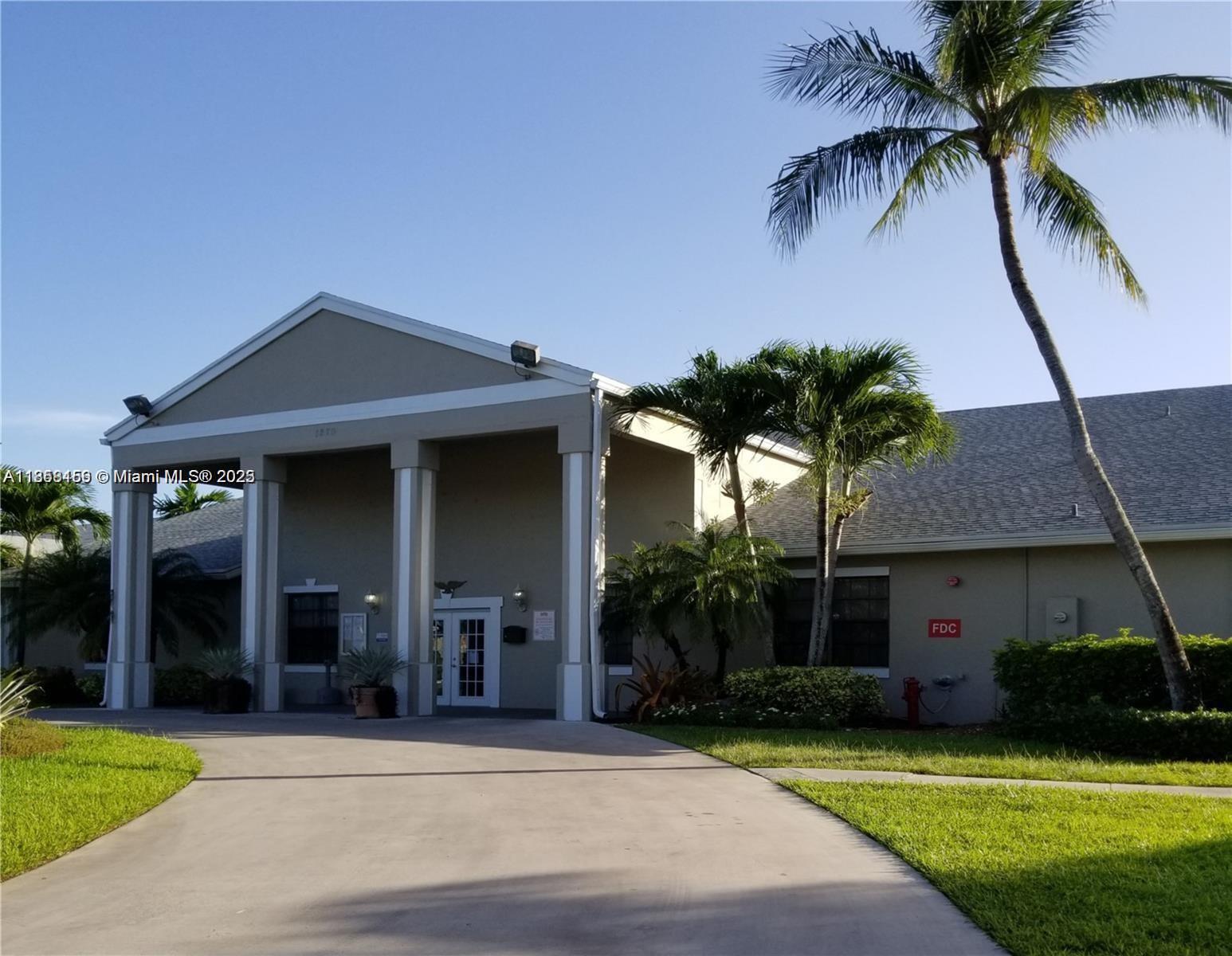 A single-story building with a covered entrance, white columns, and palm trees on a sunny day — 889 Hamilton Dr # 889I, Homestead FL 33034, HOMESTEAD, FL