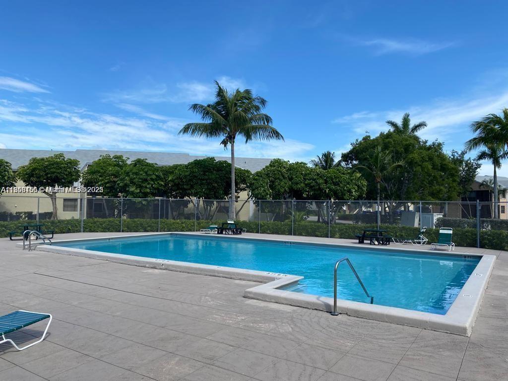 An outdoor swimming pool is surrounded by a concrete deck, a chain-link fence, and palm trees — 889 Hamilton Dr # 889I, Homestead FL 33034, HOMESTEAD, FL