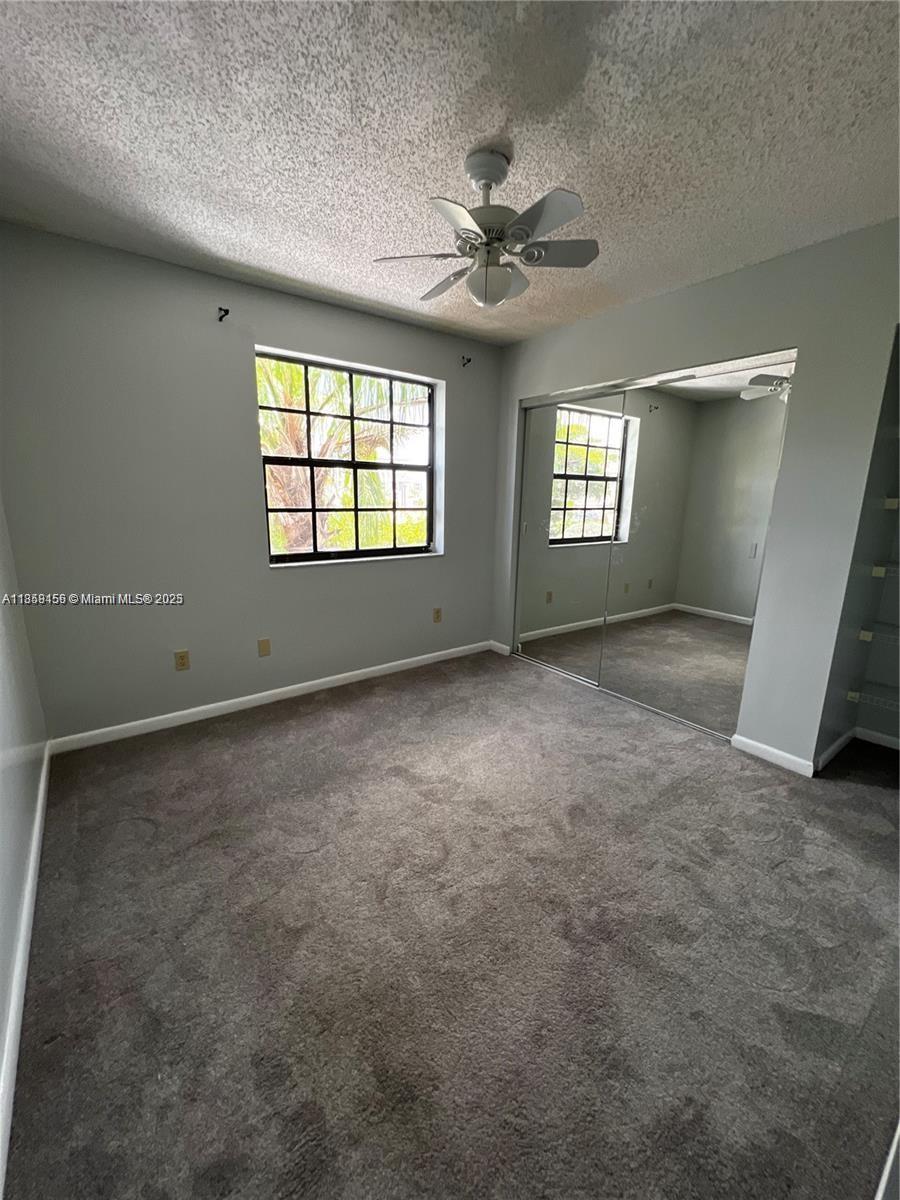 A bedroom with gray walls, carpeted flooring, a ceiling fan, and mirrored closet doors — 889 Hamilton Dr # 889I, Homestead FL 33034, HOMESTEAD, FL