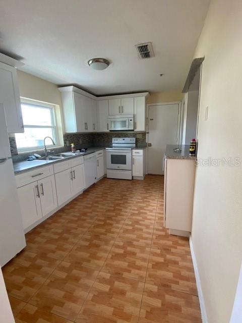 A kitchen with white cabinets, light countertops, a white stove, and wood-look tile flooring — 3131 LITTLE SOUND DRIVE, ORLANDO, FL